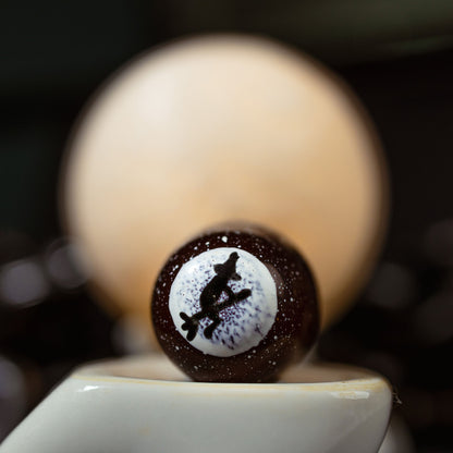 Close-up of a billiard ball with a design on top, blurred pool table in the background