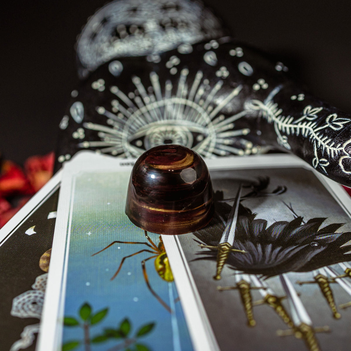 Close-up of a tarot card with a crystal ball and decorative handle on a dark background.