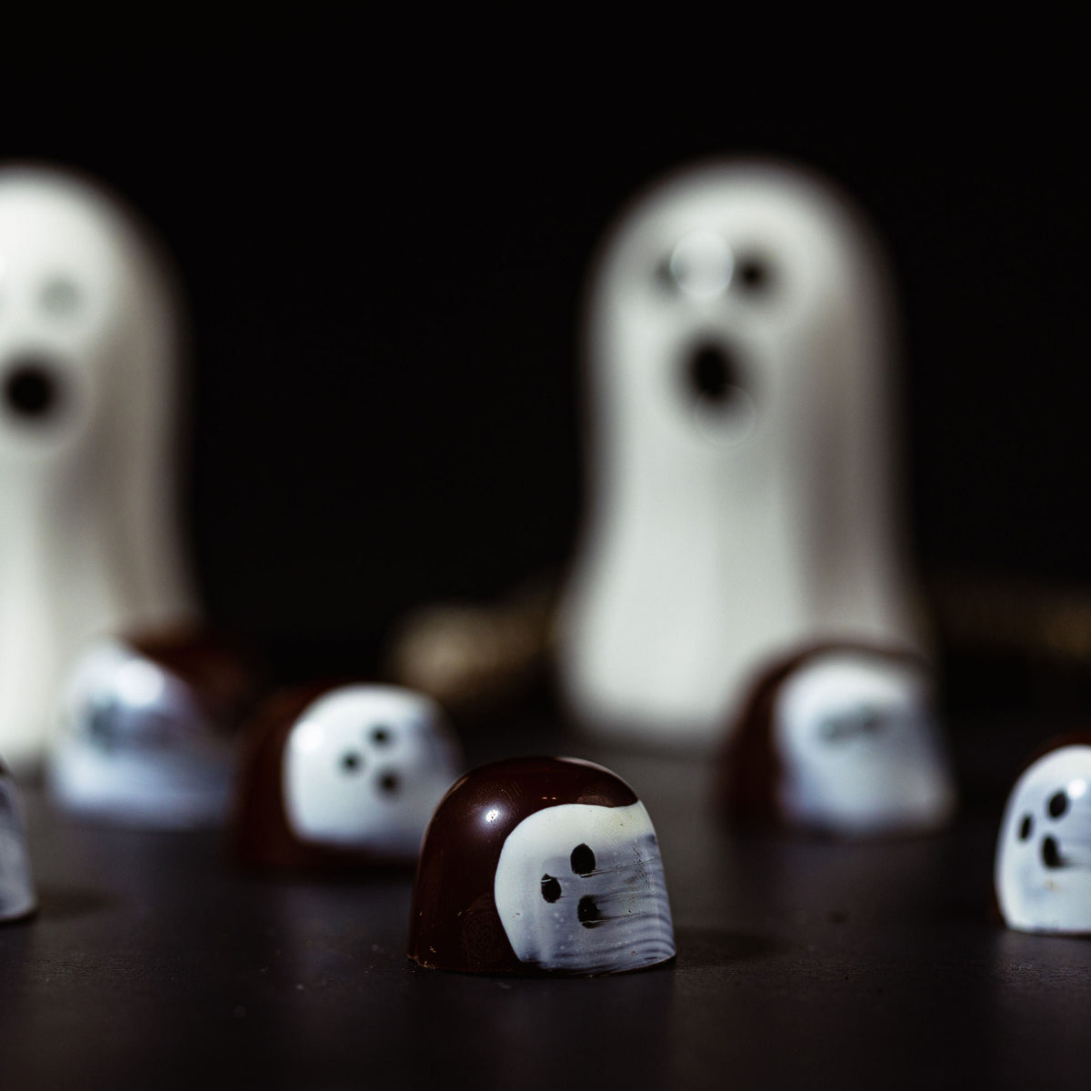 Ghost-shaped candies on a dark background