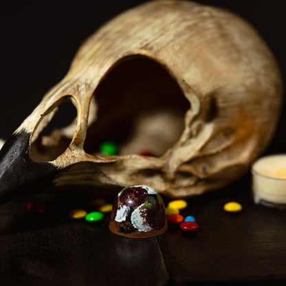 Skull with candles and colorful stones on a dark surface